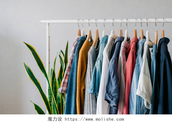 灰色背景下的一个架上挂满衣服衣橱，挂在衣架上的衣服，客厅的扶手上时尚的衣柜选择,